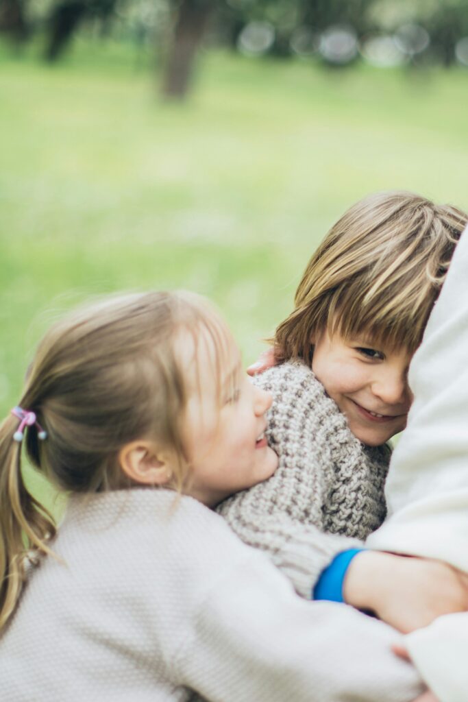 Two children smiling and hugging outdoors, conveying warmth and togetherness.